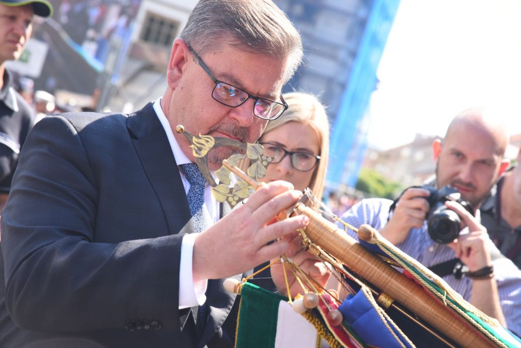 Hejtman Ústeckého kraje Jan Schiller připevňuje stuhu na prapor .jpg